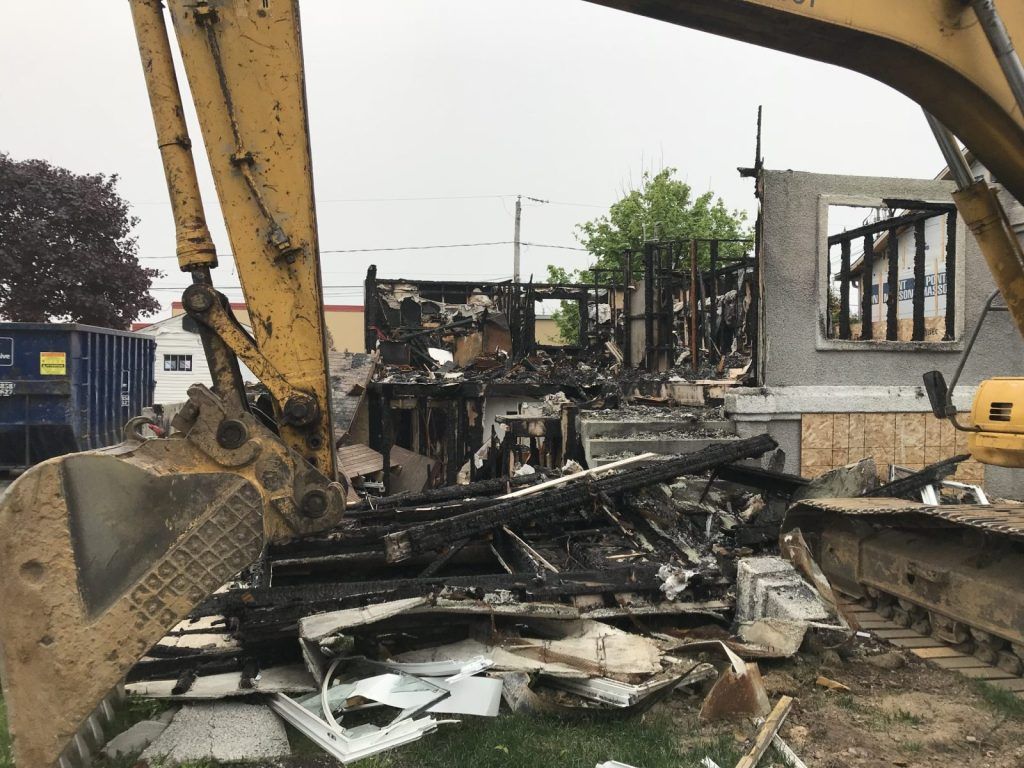 Bras de pelle hydraulique triant les débris de bois et de maçonnerie d'un bâtiment démoli