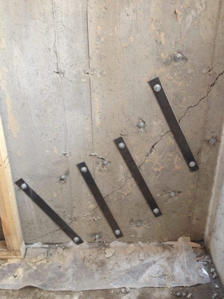 Agrafes métalliques posées en travers des fissures d'un mur de fondation en béton