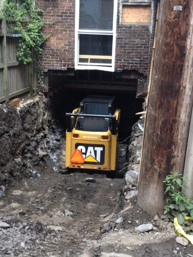 Chargeur compact CAT travaillant dans un espace restreint entre deux murs de fondation