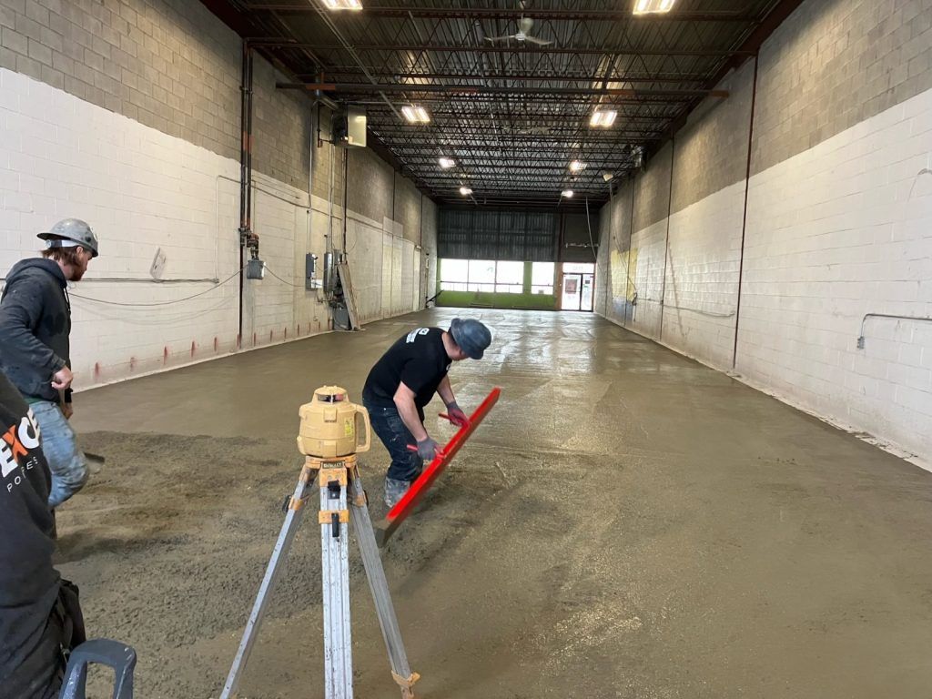 Deux ouvriers finissant une dalle de béton commerciale avec un niveau laser