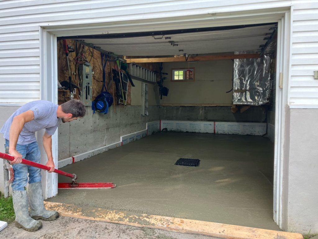 Ouvrier finissant à la main une dalle de béton de garage résidentiel