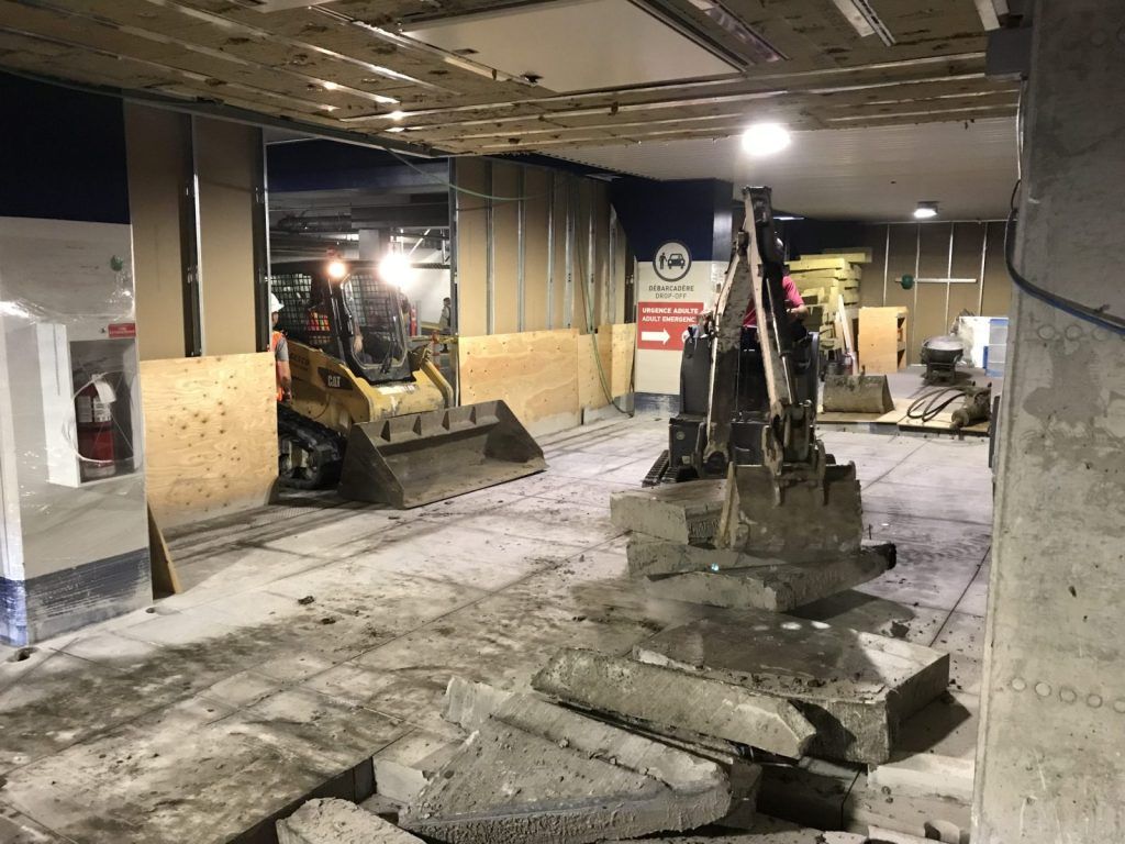 Chargeur compact cassant une dalle de béton à l'intérieur d'un local commercial