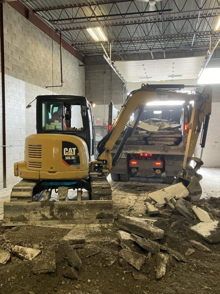 Pelle CAT et chargeur compact évacuant les morceaux d'une dalle de béton sciée