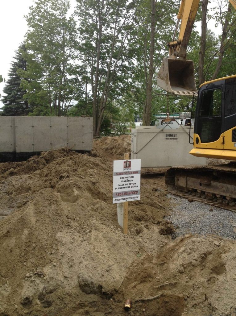 Terrain excavé avec murs de fondation et pelle hydraulique lors d'une installation septique
