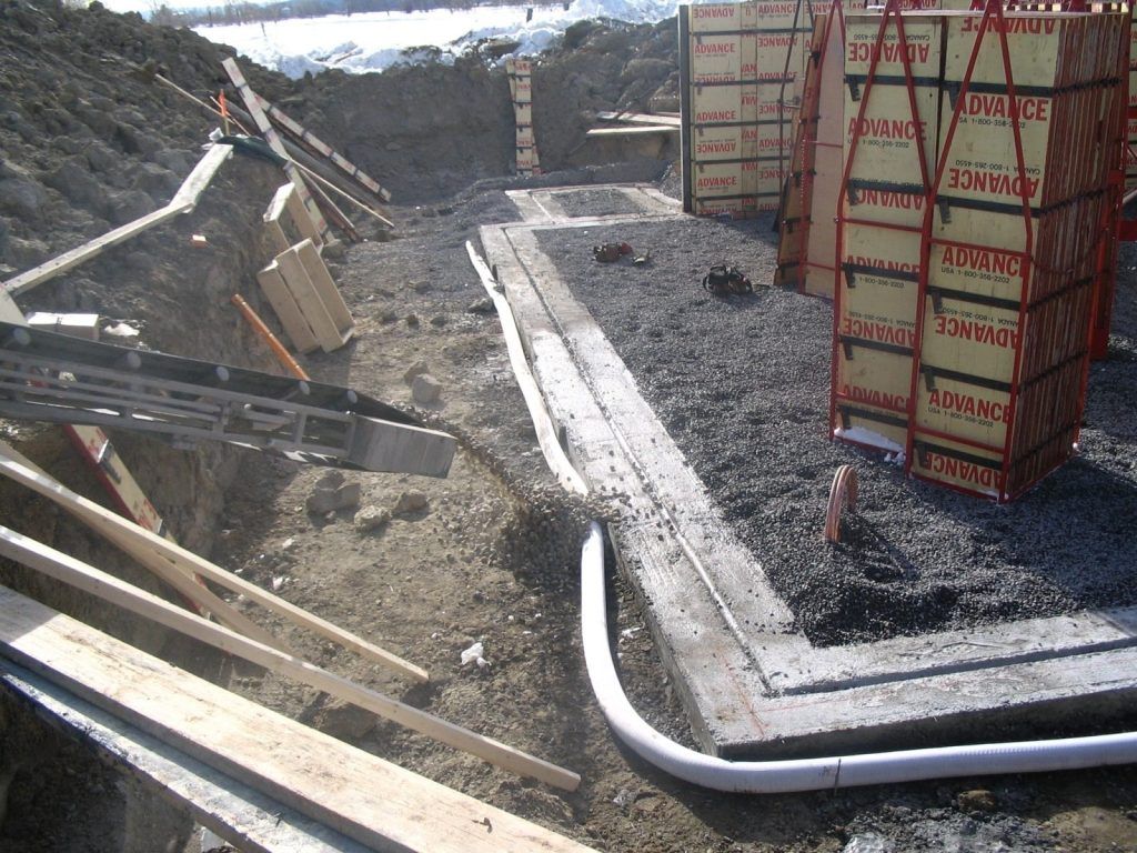 Bordure de béton coffrée bordant une surface de pierre concassée épandue
